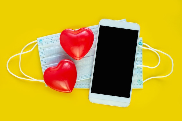 Valentine Day online congratulations, on-line Shopping. Smartphone, Medical mask and red hearts.