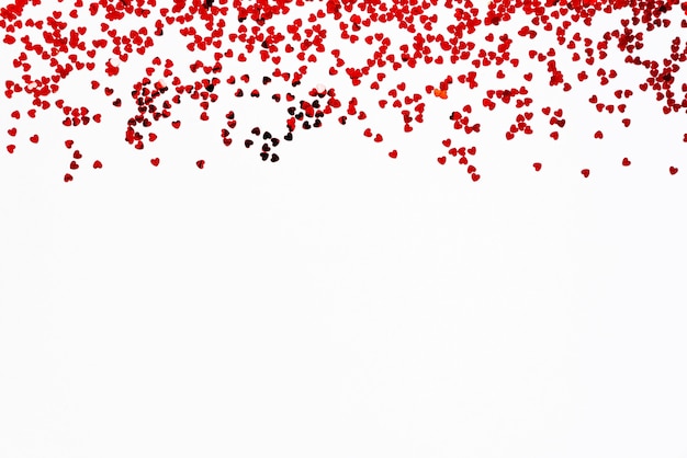 Valentine's Day background. a frame of scattered heart shaped confetti over white background.