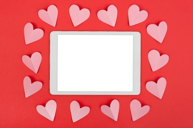 Valentine's Day background with touchpad and paper hearts. Flat lay.