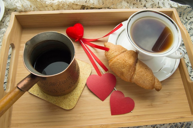 Valentine's day Breakfast croissant and coffee is served in a tray with heart