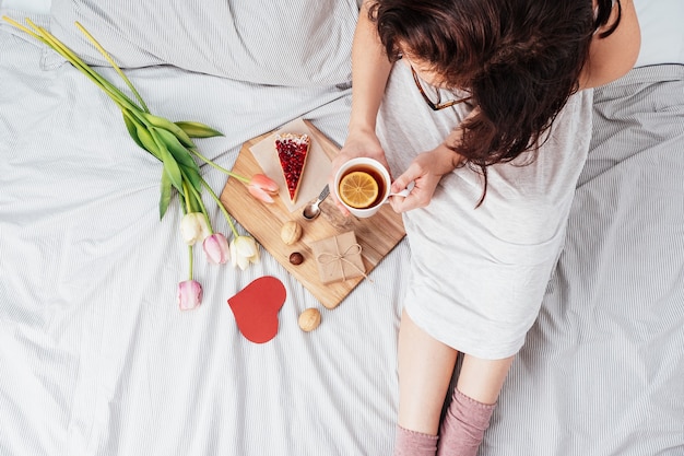 Valentine's Day. Breakfast, a gift and flowers for the girl you love. Girl in bed with flowers on February 14.