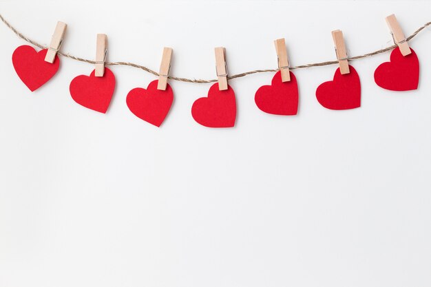 Valentine's day card. White background with red hearts on clothespins.