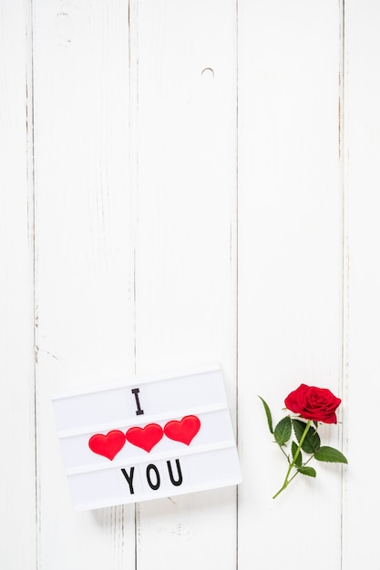 Valentine's day concept fresh red rose flower and text I LOVE YOU on lightbox on white wooden background