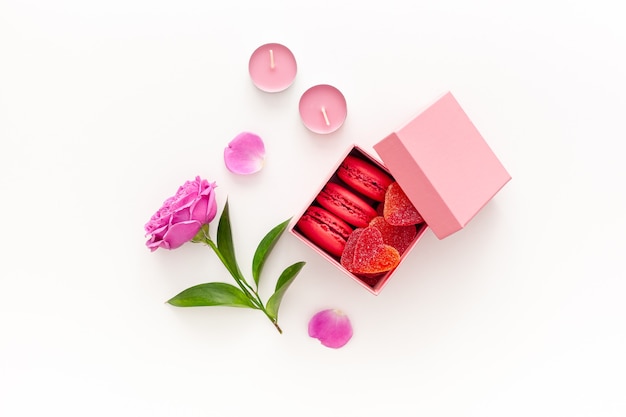 Valentine's day concept. Pink box with marmalade and macaroons and a beautiful rose on a pink table