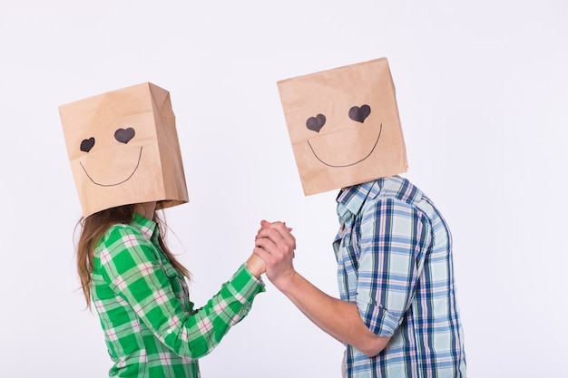 Photo valentine's day concept - young love couple with bags over heads on white background