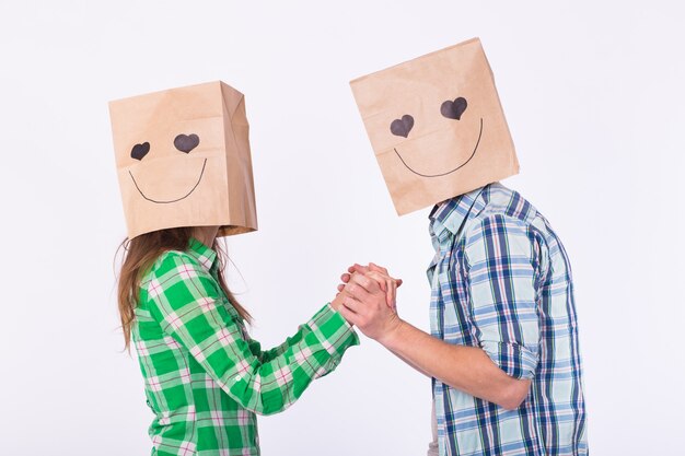 Photo valentine's day concept - young love couple with bags over heads on white background