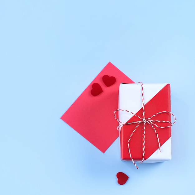 Valentine's Day design concept - Red, white wrapped gift box isolated on light blue color background