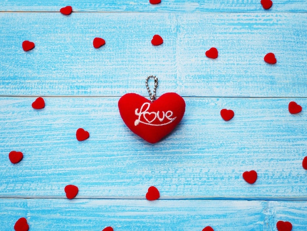 Valentine's day greeting card background. Key chain red heart shape with word love on blue wooden table.