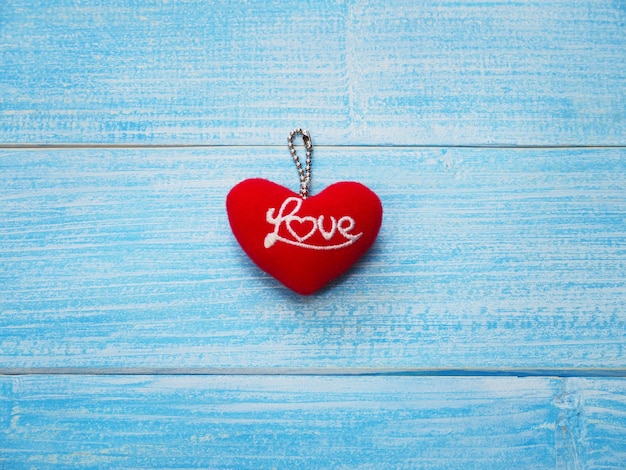 Valentine's day greeting card background with copy space. Key chain red heart shape with word love on blue wooden table.