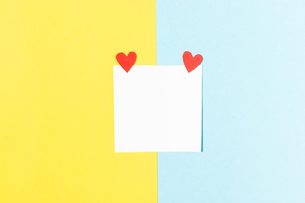 Valentine's day greeting card white square for notes with red hearts on blue and yellow background