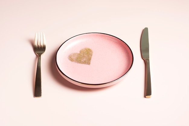 Valentine's Day table setting, pink plate with golden heart on powdery background