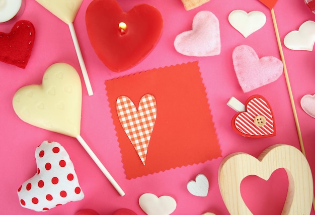 Valentine's gift with sweets and decor on pink background top view