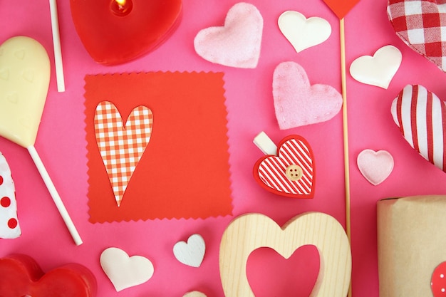 Valentine's gift with sweets and decor on pink background top view