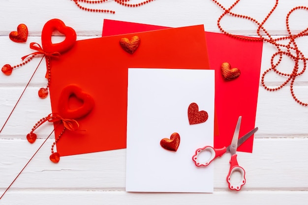 Valentines day background. Handmade gift greeting card creating, cut and paste, craft paper, felt and diy tools on white wood. Above view, flat lay