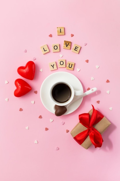 Valentines day card Cup of coffee with chocolate candies and gift box on pink