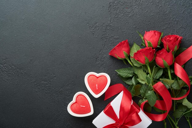 Valentines day card Rose red flowers brownie cookies and chocolate candy on heart shaped gift box with wine on black background Mothers or Womens Day greeting card Top view flat lay