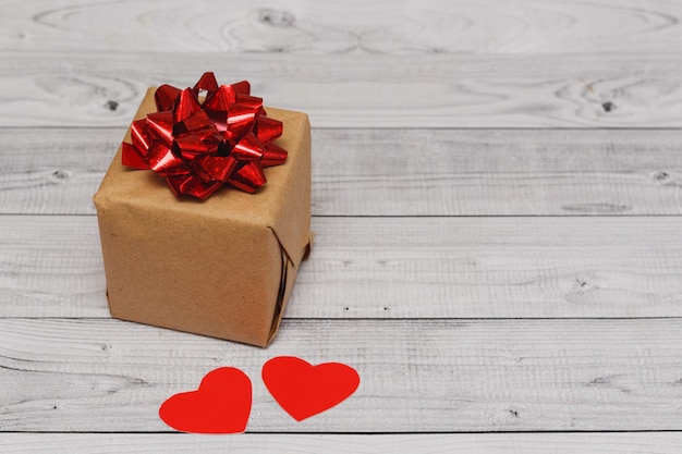 Valentines day card with gift box and hearts on wooden background