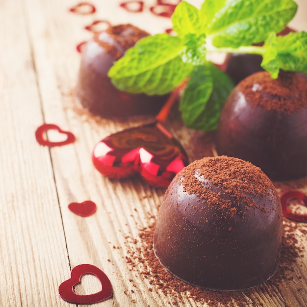 Valentines day composition with chocolate candies and hearts on vintage wooden surface. Toned photo with copy space for text