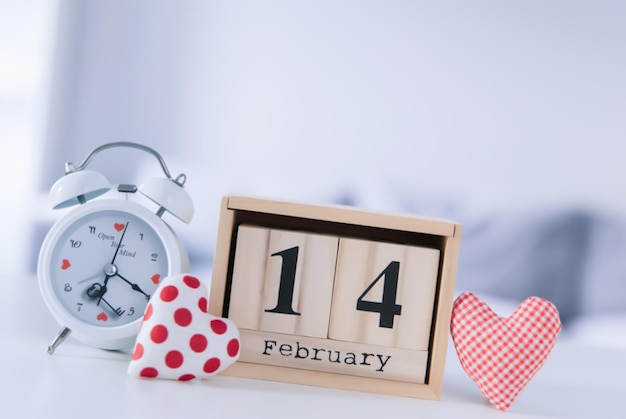 Valentines day concept Hand make yarn red heart beside wooden block calendar set on Valentines date 14 February on table and bright room background Happy valentine day