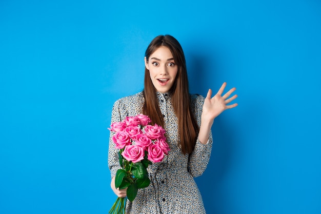 Valentines day concept surprised pretty girl holding bouquet of flowers from lover looking amazed an...