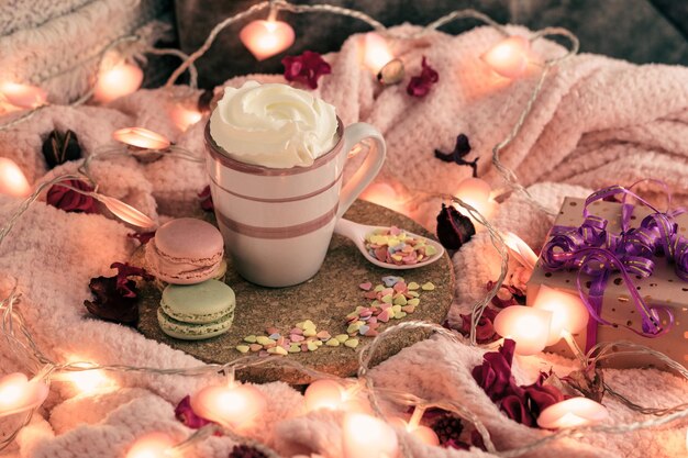 Valentines day concept with cup full of cream and a lot of small sweet hearts Pink lights