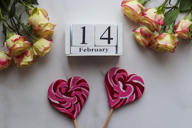 Photo valentines day concept wooden calendar 14 february beautiful flowers and heart shaped candies