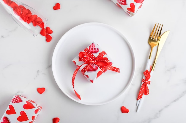 Valentines day dinner background with gifts red hearts fork and knife on white marble romantic