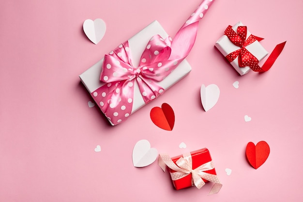 Valentines day gift boxes with paper hearts on pink background