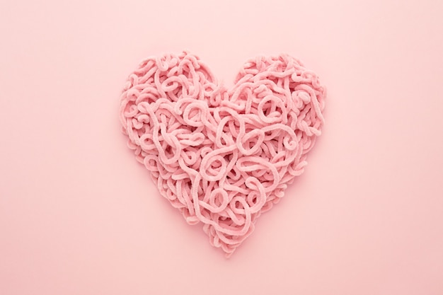 Valentines Day Heart made of yarn on pink background. Copy space, Flat lay. Compound love symbol.