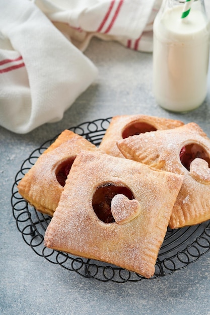 Valentines day heart shaped Hand pies Mini puff pastry or hand pies stuffed with apple and sprinkle sugar powder in plate Idea for homemade romantic snack Valentines day Top view Copy space