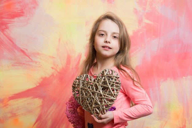 Photo valentines day holiday and party celebration small girl with love heart child girl on colorful background kid with decorative love heart childhood and happiness