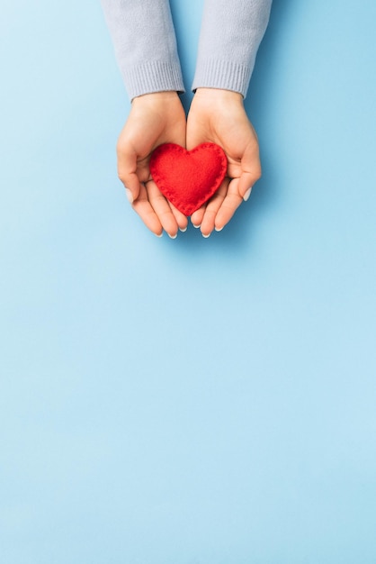 Valentines Day love expression concept with red heart on woman palms. Top view with copy space