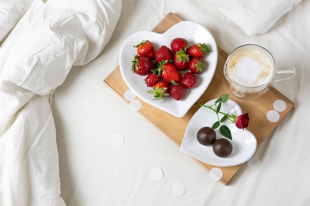 Valentines day morning Breakfast in bed Strawberries chocolate candy and coffee on a wooden tray