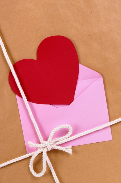 Valentines day red heart shape card or gift tag, brown paper package parcel background, copy space, vertical