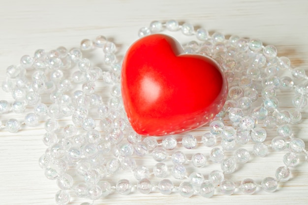 Valentines day red heart with glass beads on a white wooden surface with glass beads. flat lay, space for text.