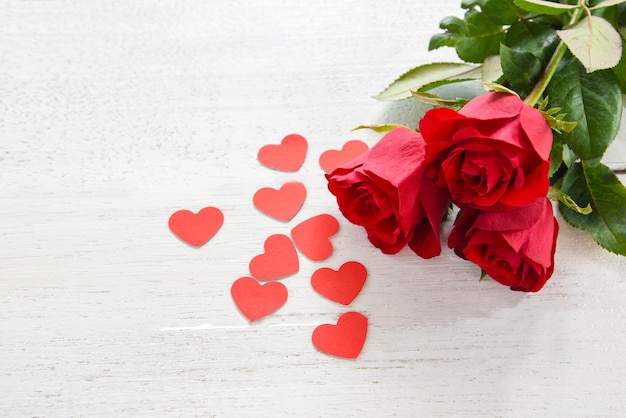 Valentines day red rose flower on white wooden background / Romantic love small red heart 