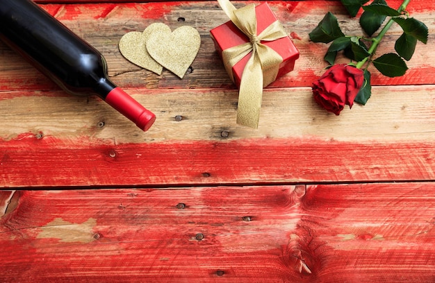 Valentines day Red wine bottle rose and a gift on wooden background