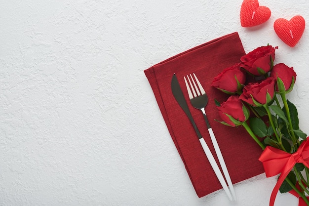 Valentines day romantic table setting Empty or closeup of a dinner black plate knife fork and decorative silk hearts on white background Holiday concept Copy space for inscriptions