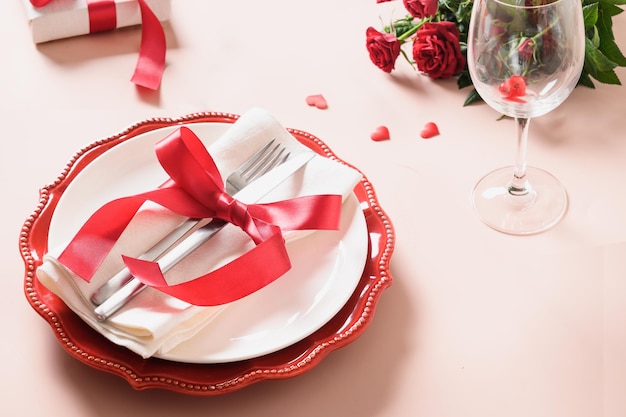 Valentines day table setting with red decoration, gift and roses.