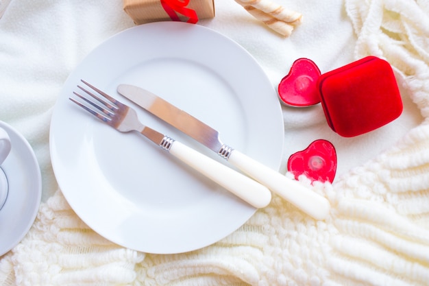 Valentines day tablesetting with red velvet ring box, candles and silverware