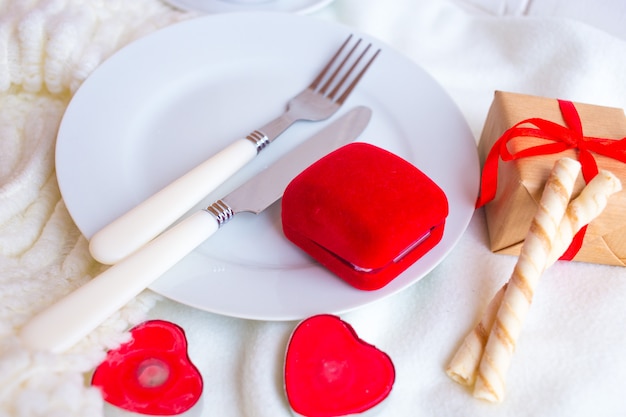 Valentines day tablesetting with red velvet ring box, candles and silverware