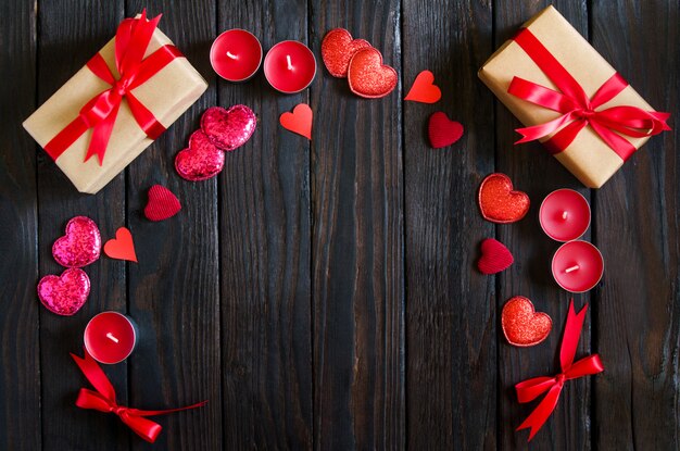 Valentines day wooden background with red heart, gifts and candles. Gifts for Valentines day. Black wooden background