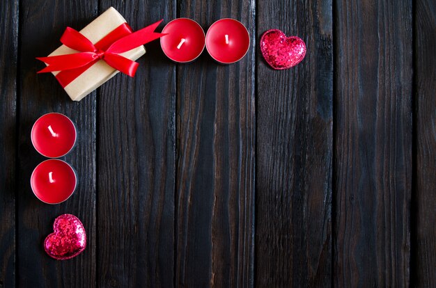 Valentines day wooden background with red heart, gifts and candles. Gifts for Valentines day. Black wooden background