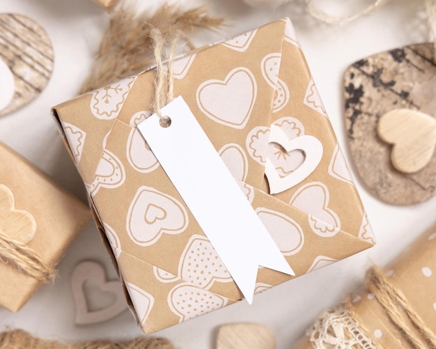 Valentines kraft paper wrapped present with gift tag and hearts close up. Spring scene with blank label. Rustic, cottage chic or bohemian mockup, copy space