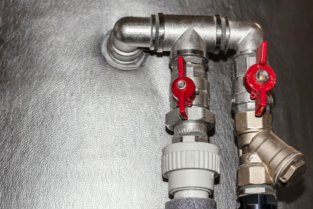 Valves on Pipes of Water Heating System of House in Winter. Red Water Tap into Buffer Storage Tank.