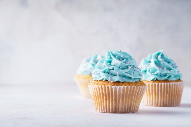 Vanilla cupcakes with blue frosting decorated with sprinkles.