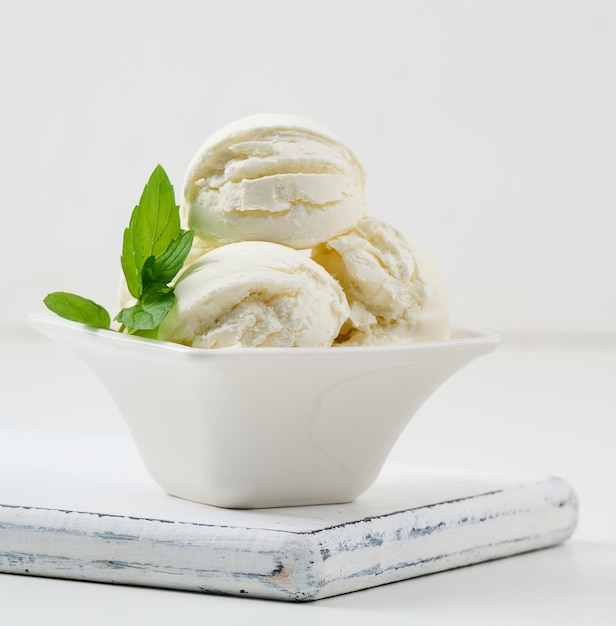 Vanilla ice cream balls with green mint leaf in a white ceramic plate