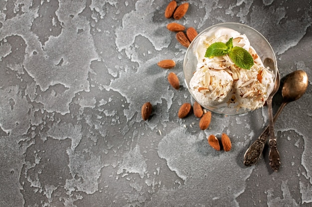 Vanilla ice cream with almonds on a gray concrete background. Top view