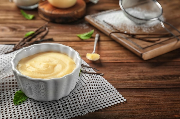 Vanilla pudding in ceramic bowl on wooden table