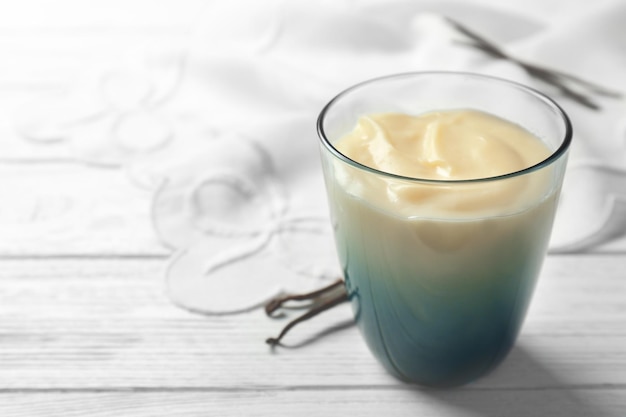 Vanilla pudding in glass on white wooden background